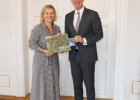 Regierungspräsident Walter Jonas begrüßt die tschechische Generalkonsulin, Dr. Ivana Červenková, an der Regierung der Oberpfalz . Beide halten dabei Gastgeschenke in den Händen.