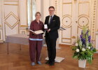 Dr. Magdalena Helmig und Regierungsvizepräsident Florian Luderschmid zeigen Bundesverdienstkreuz mit zugehöriger Urkunde